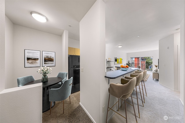 kitchen with black fridge and light colored carpet