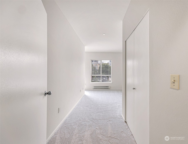 corridor featuring light carpet and a baseboard heating unit