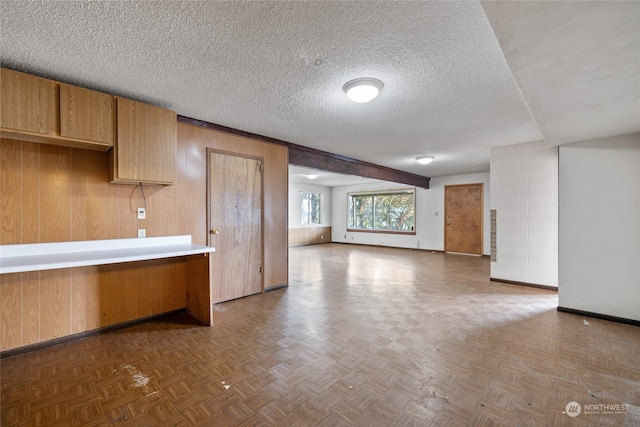 kitchen with dark parquet floors, wood walls, and a textured ceiling