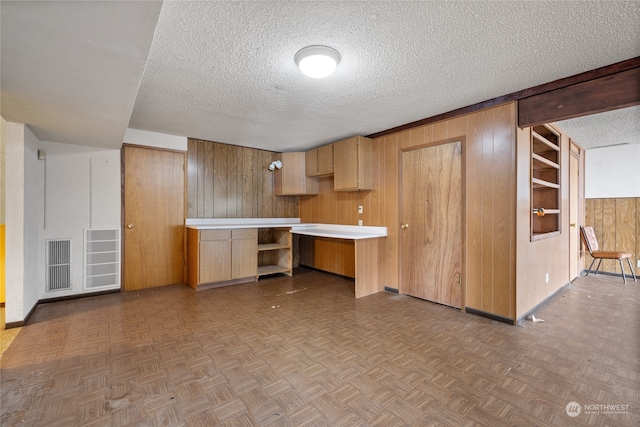 kitchen with a textured ceiling, wooden walls, and light parquet floors