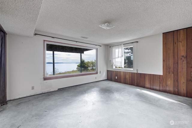 unfurnished room featuring wood walls and a textured ceiling