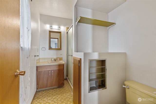 bathroom with a shower with door, vanity, and toilet