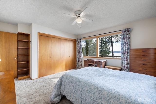 carpeted bedroom with ceiling fan, a textured ceiling, and a closet