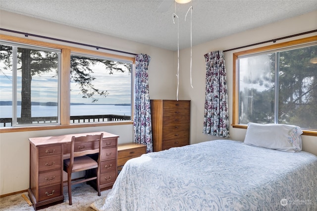 bedroom featuring light carpet, ceiling fan, and a textured ceiling