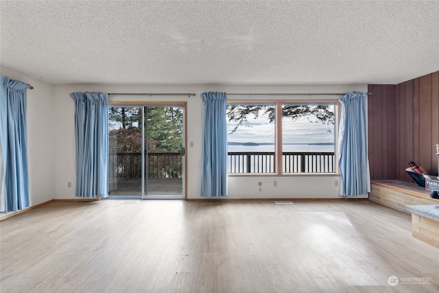 empty room featuring hardwood / wood-style flooring, wood walls, and a textured ceiling