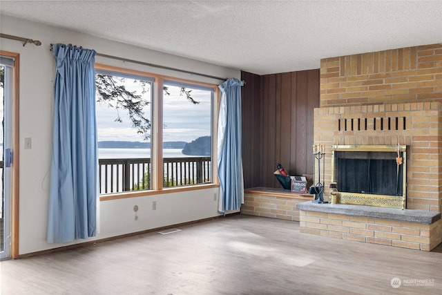 unfurnished living room with a textured ceiling, a fireplace, and hardwood / wood-style floors