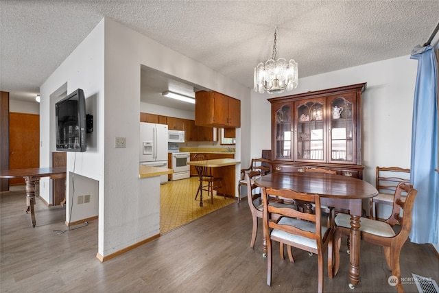 dining space featuring a textured ceiling, wood-type flooring, sink, and a chandelier