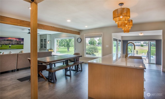 kitchen featuring pendant lighting, a center island with sink, ceiling fan with notable chandelier, and dark hardwood / wood-style flooring