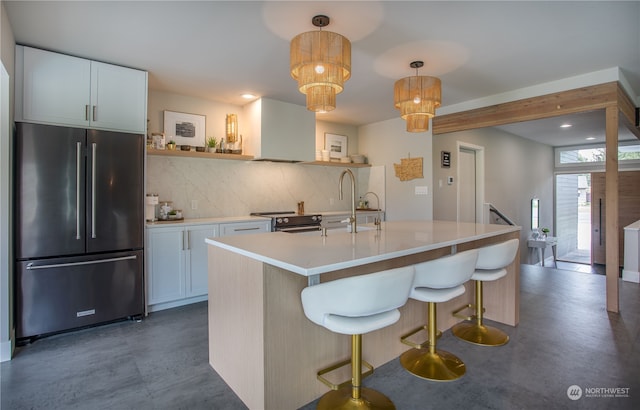 kitchen with white cabinetry, an island with sink, pendant lighting, stainless steel appliances, and an inviting chandelier