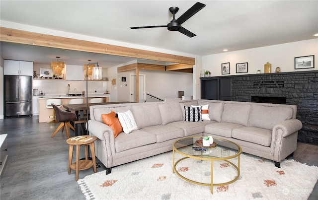 living room featuring ceiling fan, a fireplace, and sink