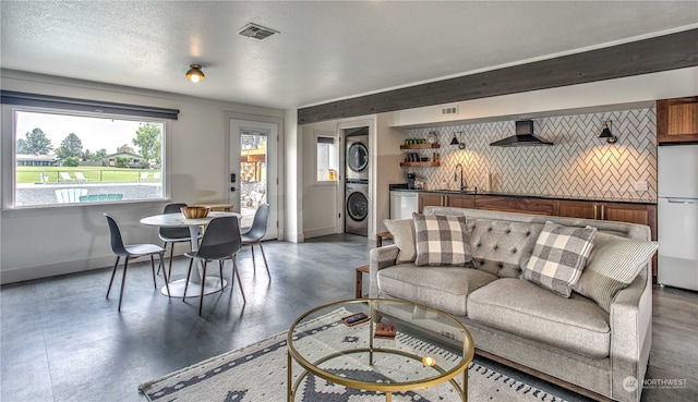 living room featuring a textured ceiling and stacked washing maching and dryer