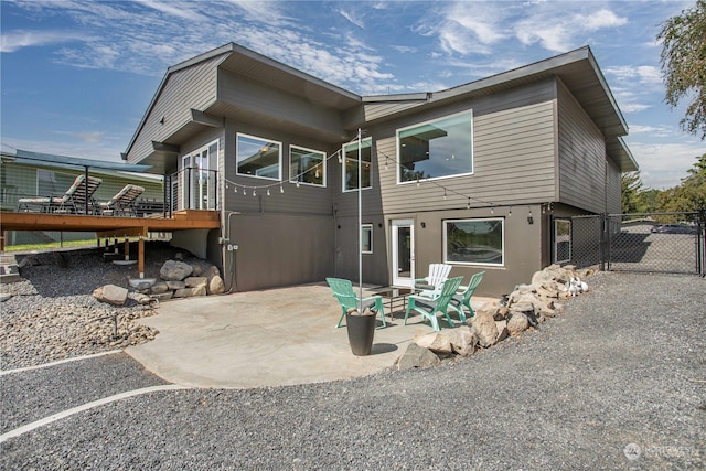 back of property featuring a wooden deck, a patio area, and an outdoor fire pit