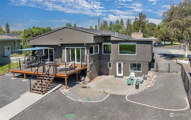 rear view of house featuring a wooden deck and a patio area