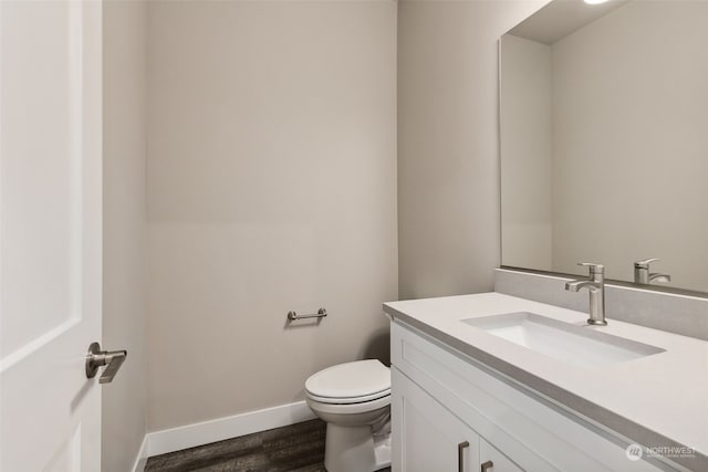 bathroom featuring wood-type flooring, vanity, and toilet