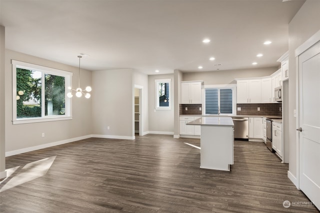 kitchen with tasteful backsplash, dark wood-type flooring, white cabinetry, appliances with stainless steel finishes, and a center island