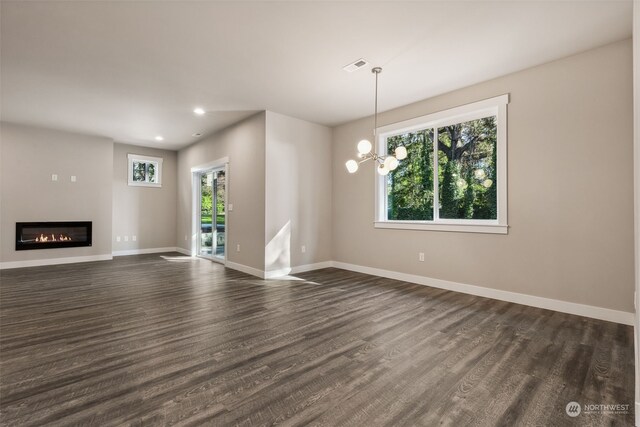 unfurnished living room featuring a notable chandelier, dark hardwood / wood-style floors, and a wealth of natural light