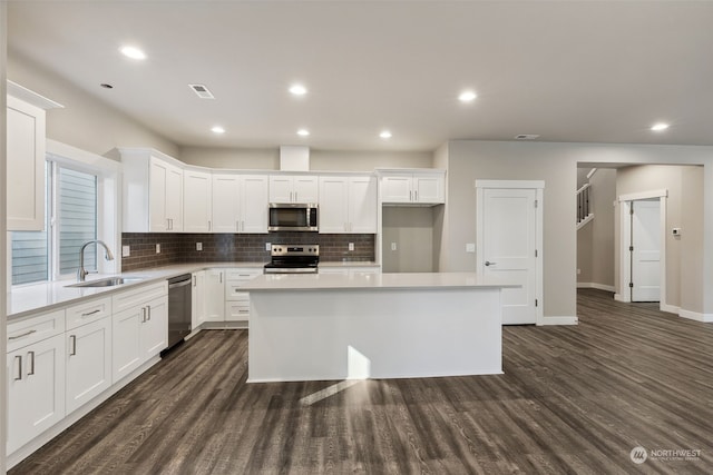 kitchen with a kitchen island, sink, stainless steel appliances, and white cabinetry