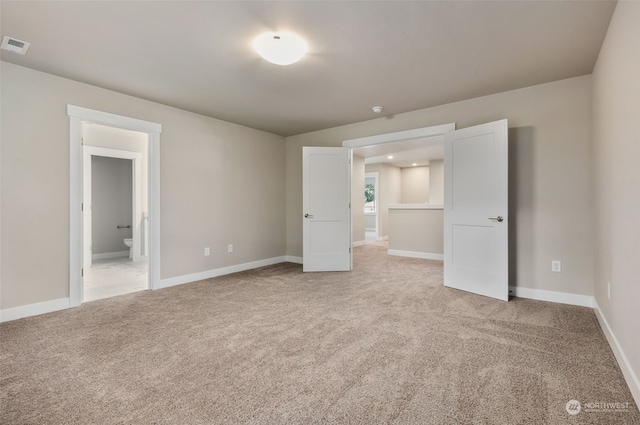 unfurnished bedroom with light colored carpet and ensuite bathroom