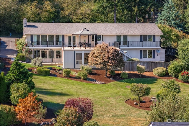 view of front of home with a balcony and a front lawn