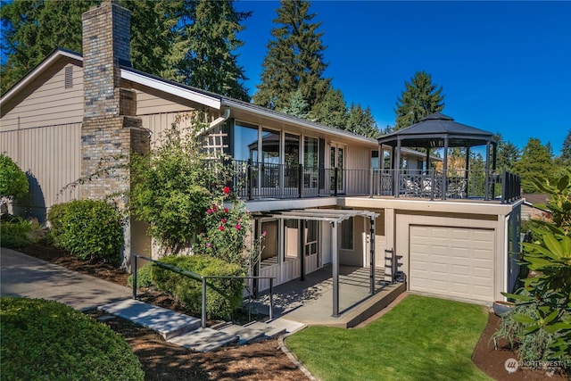 back of house with a lawn, a gazebo, a balcony, and a garage