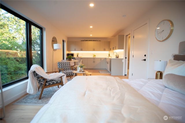 bedroom with light hardwood / wood-style flooring, sink, and multiple windows