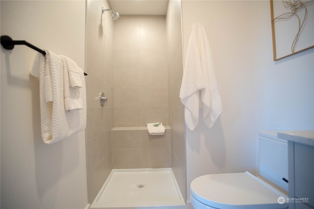 bathroom with a tile shower and toilet