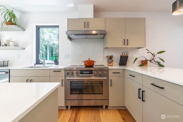 kitchen featuring appliances with stainless steel finishes, sink, light hardwood / wood-style flooring, and light stone counters