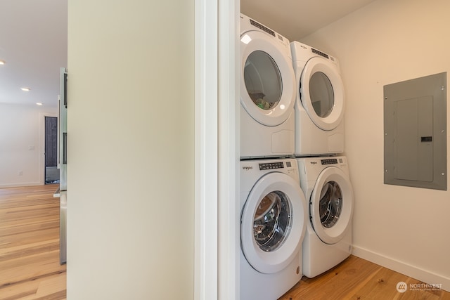 laundry room with light hardwood / wood-style floors, electric panel, and stacked washer and clothes dryer