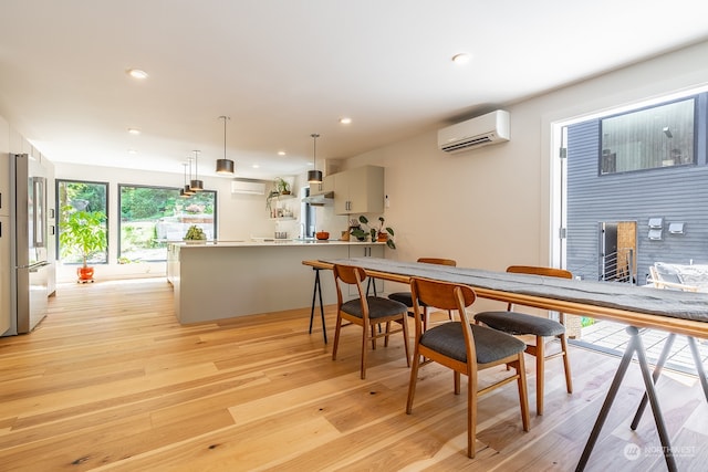 dining space with light wood-type flooring, a wall unit AC, and a fireplace