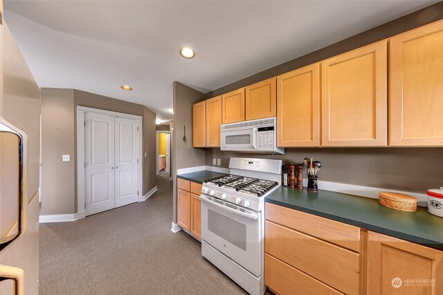 kitchen featuring white appliances, light brown cabinets, and light colored carpet