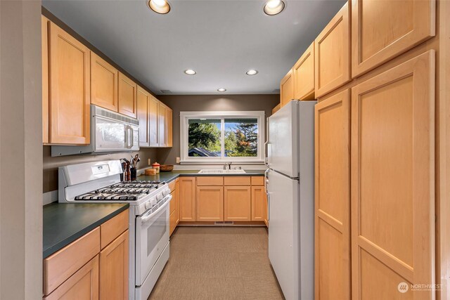 kitchen featuring light brown cabinetry, sink, and white appliances