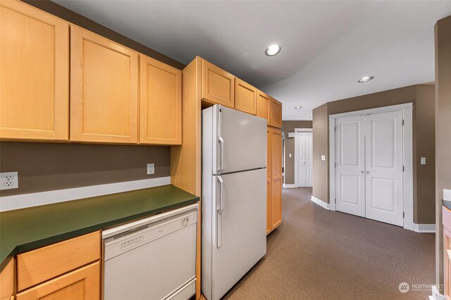 kitchen featuring dark carpet, white appliances, and light brown cabinets