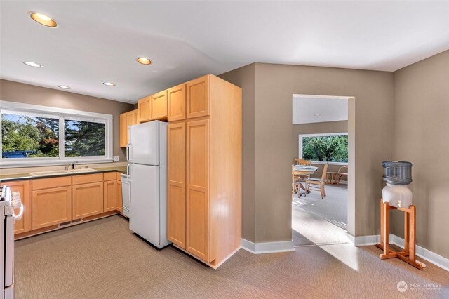 kitchen featuring light carpet, white appliances, light brown cabinets, and plenty of natural light