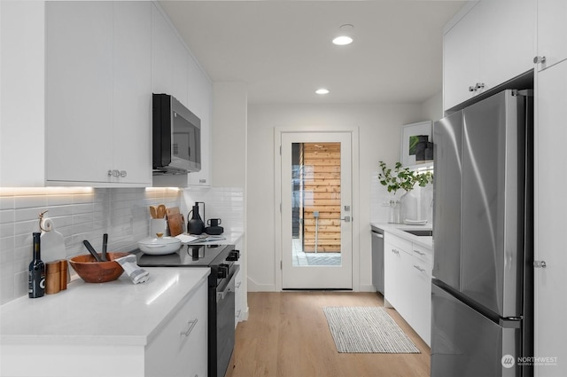 kitchen featuring white cabinetry, backsplash, light wood-type flooring, and stainless steel appliances