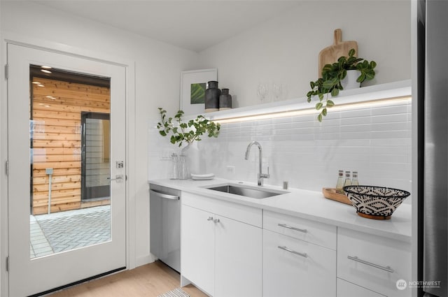 kitchen with white cabinetry, sink, dishwasher, and decorative backsplash