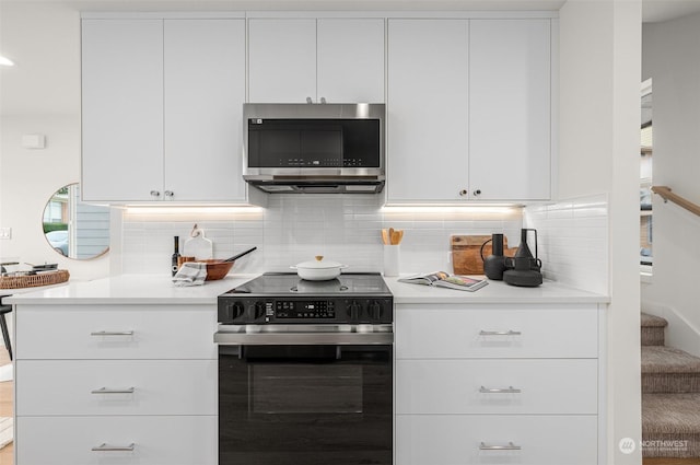 kitchen with white cabinetry, electric range oven, and decorative backsplash