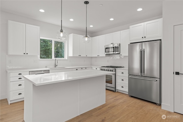 kitchen featuring a center island, appliances with stainless steel finishes, hanging light fixtures, and light hardwood / wood-style flooring