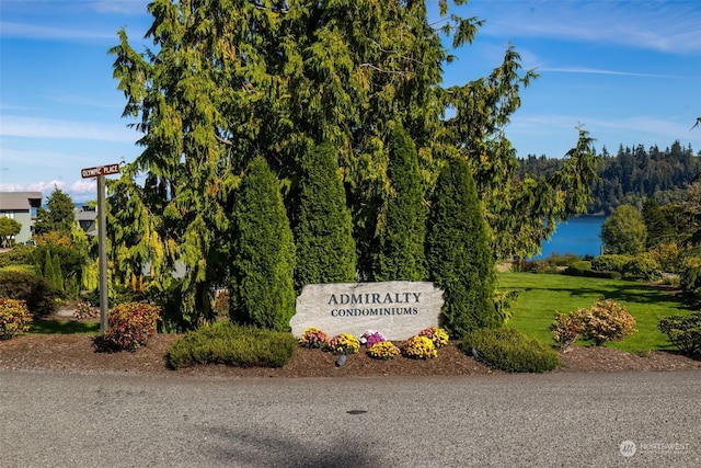 community sign featuring a lawn and a water view