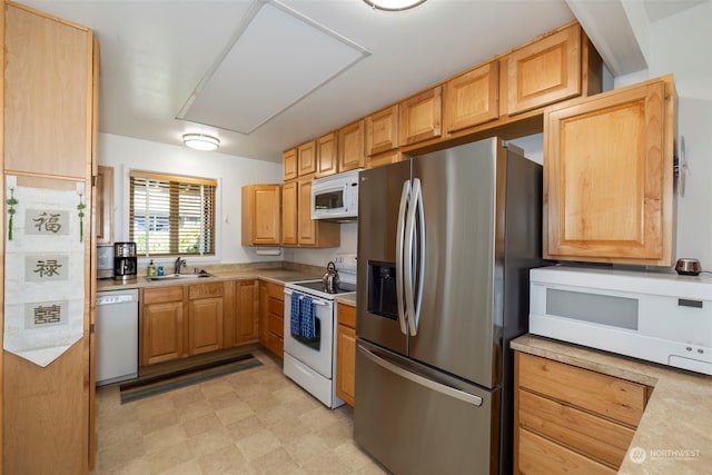 kitchen featuring light brown cabinetry, sink, and white appliances