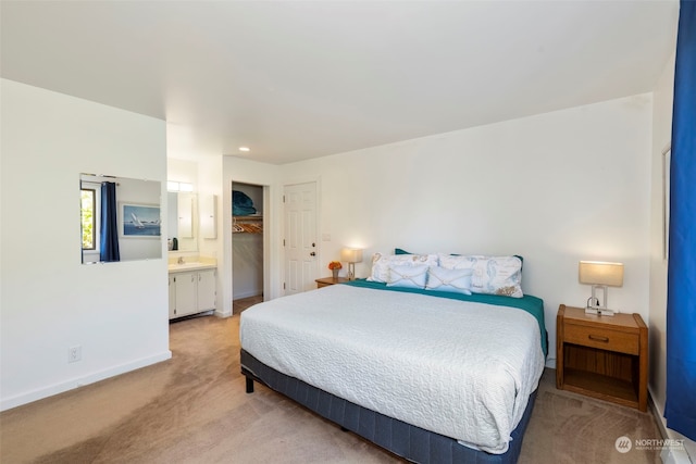 bedroom with ensuite bath, sink, and light colored carpet