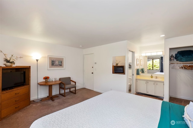 carpeted bedroom featuring sink, a closet, and ensuite bathroom