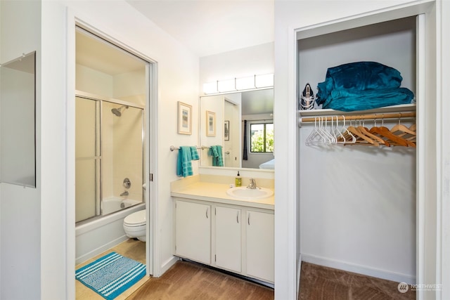 full bathroom featuring enclosed tub / shower combo, vanity, toilet, and hardwood / wood-style flooring