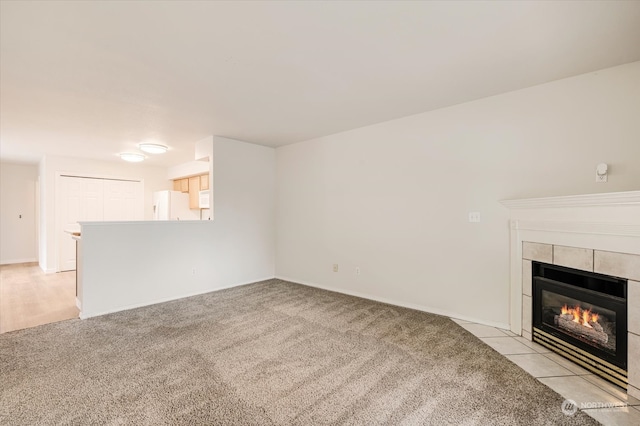 unfurnished living room with a tile fireplace and light carpet