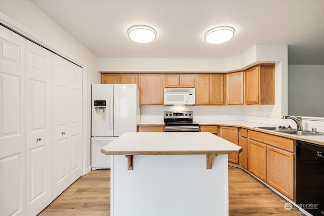 kitchen featuring white appliances, a kitchen island, a breakfast bar area, light hardwood / wood-style flooring, and sink