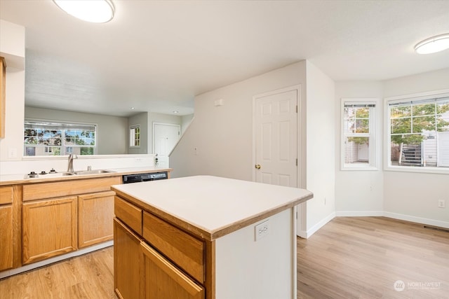 kitchen featuring light wood-type flooring, a kitchen island, sink, and a wealth of natural light