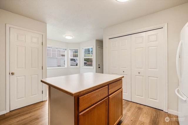 kitchen with a center island, light hardwood / wood-style flooring, and white fridge