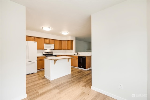 kitchen featuring sink, white appliances, a kitchen island, light wood-type flooring, and a kitchen bar