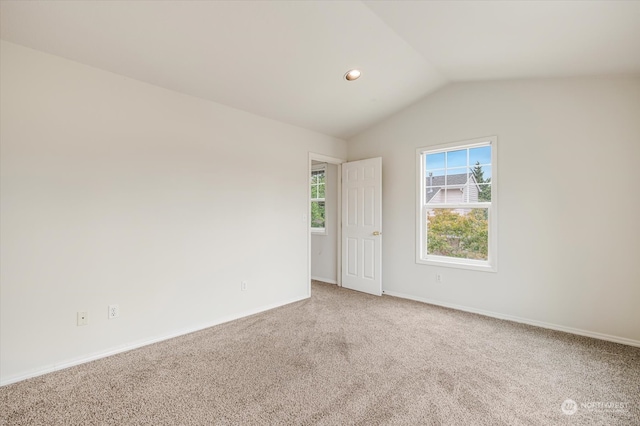 carpeted empty room featuring vaulted ceiling