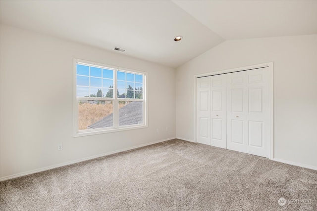 unfurnished bedroom with lofted ceiling, a closet, and carpet floors