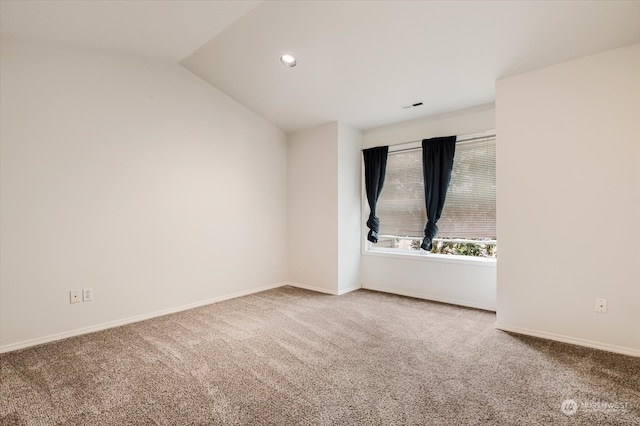 carpeted spare room featuring vaulted ceiling